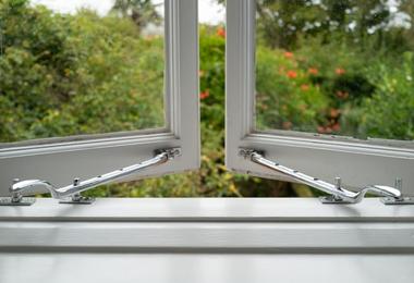 Chrome window handles with built-in window restrictors on an ajar window