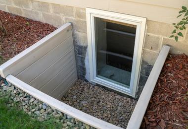 Exterior view of a basement egress window with window well in a residential Canadian home