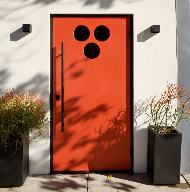 Bright orange modern entry door on a contemporary house