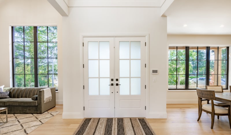 Elegant double French patio doors with glass panes and white wood frames opening to backyard