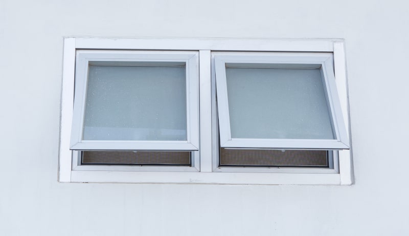 Small aluminum awning window slightly open to allow air circulation during light rain