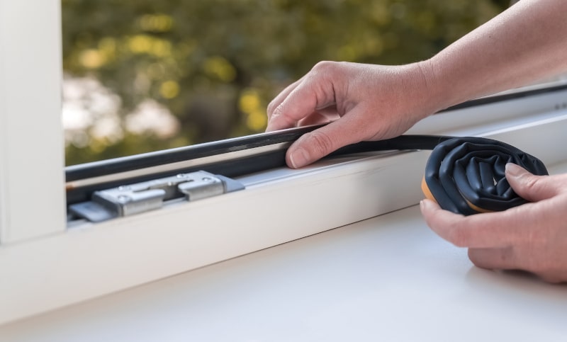 Technician installing energy-efficient window seal to improve airtightness