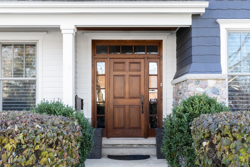 Wooden exterior door on a blue Canadian house showing natural grain and craftsmanship